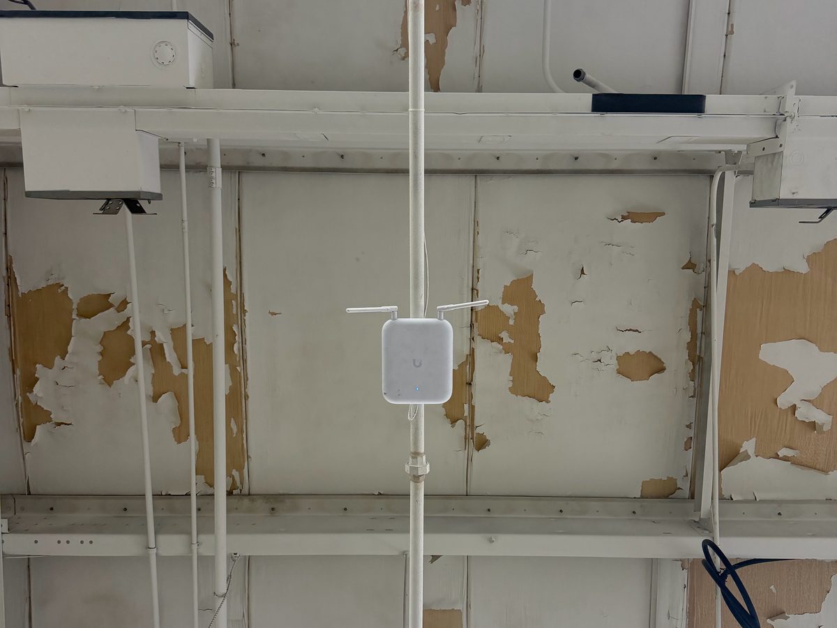 Pipe-mounted Wi-Fi access point in a shop ceiling